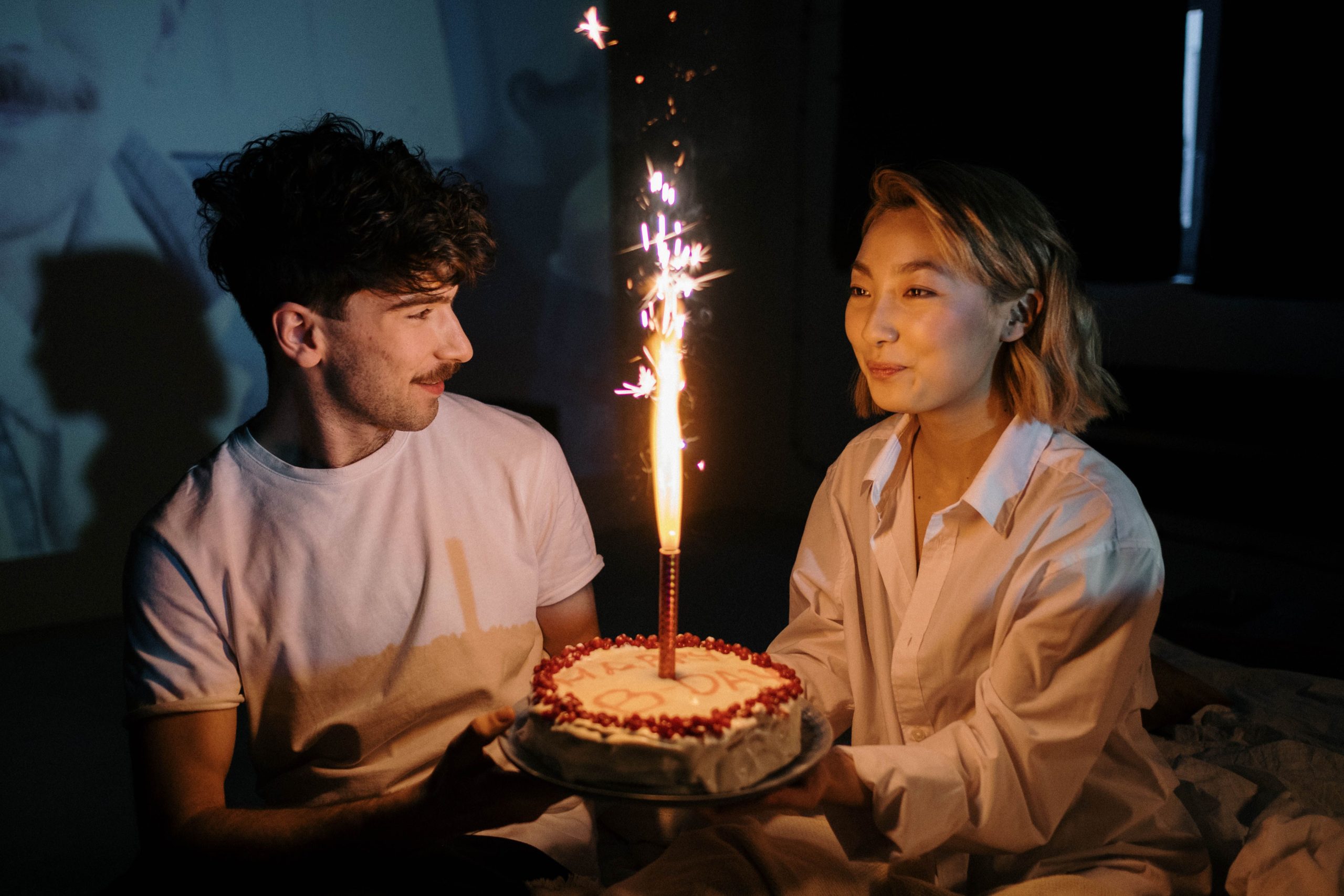 Couple célébrant un anniversaire avec un gâteau et bougie scintillante