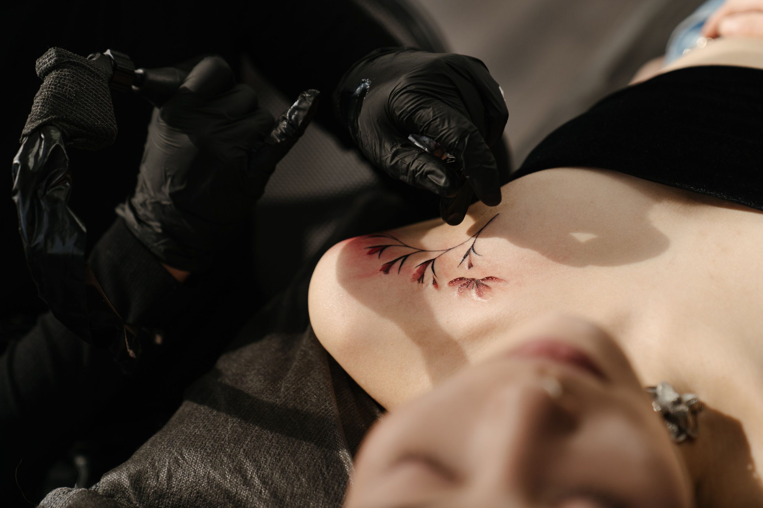 Artiste créant un tatouage floral sur une femme