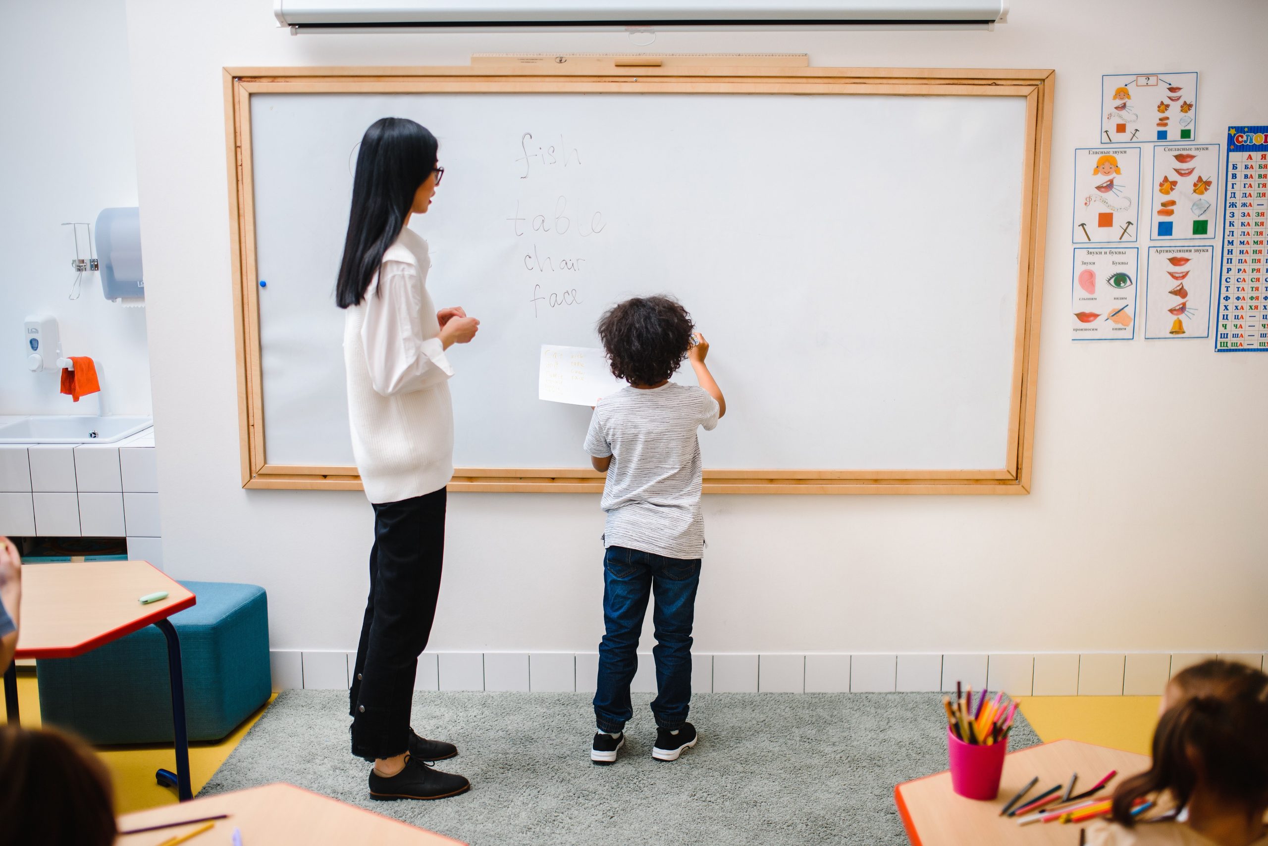 Garçon écrivant au tableau avec son professeur