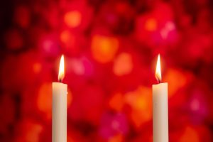 Deux bougies allumées brillent chaleureusement sur fond rouge