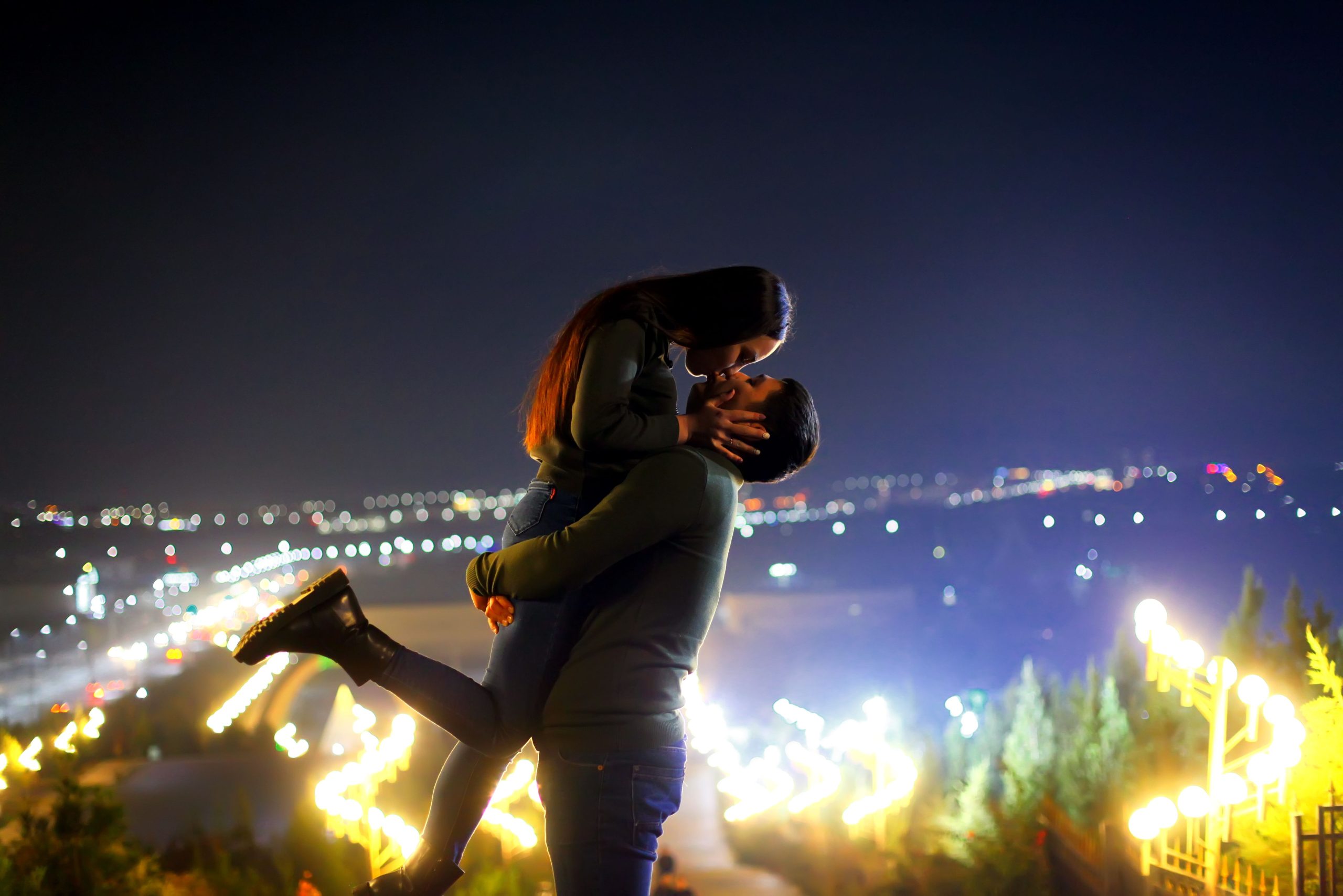 Jeune couple s'embrassant sous lumières citadines