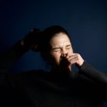 Femme éternuant sur fond bleu
