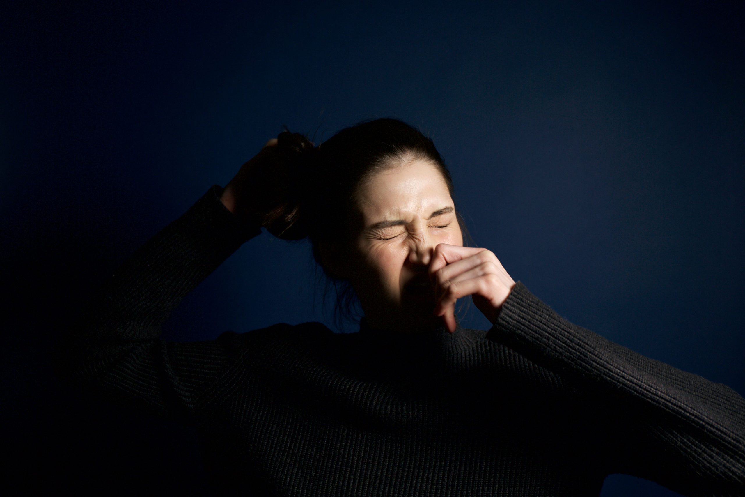 Femme éternuant sur fond bleu