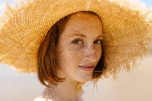 Femme souriante avec taches de rousseur et chapeau de paille