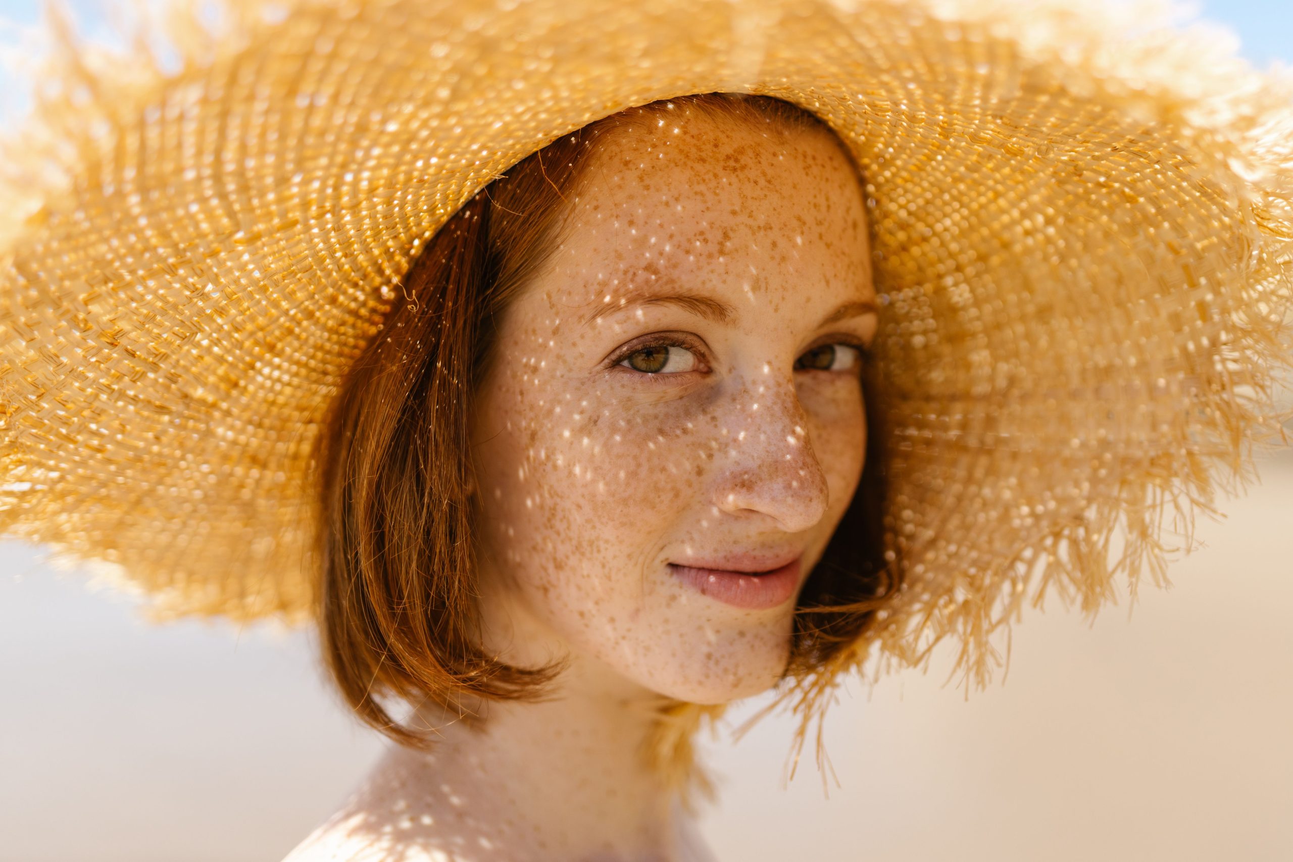 Femme souriante avec taches de rousseur et chapeau de paille