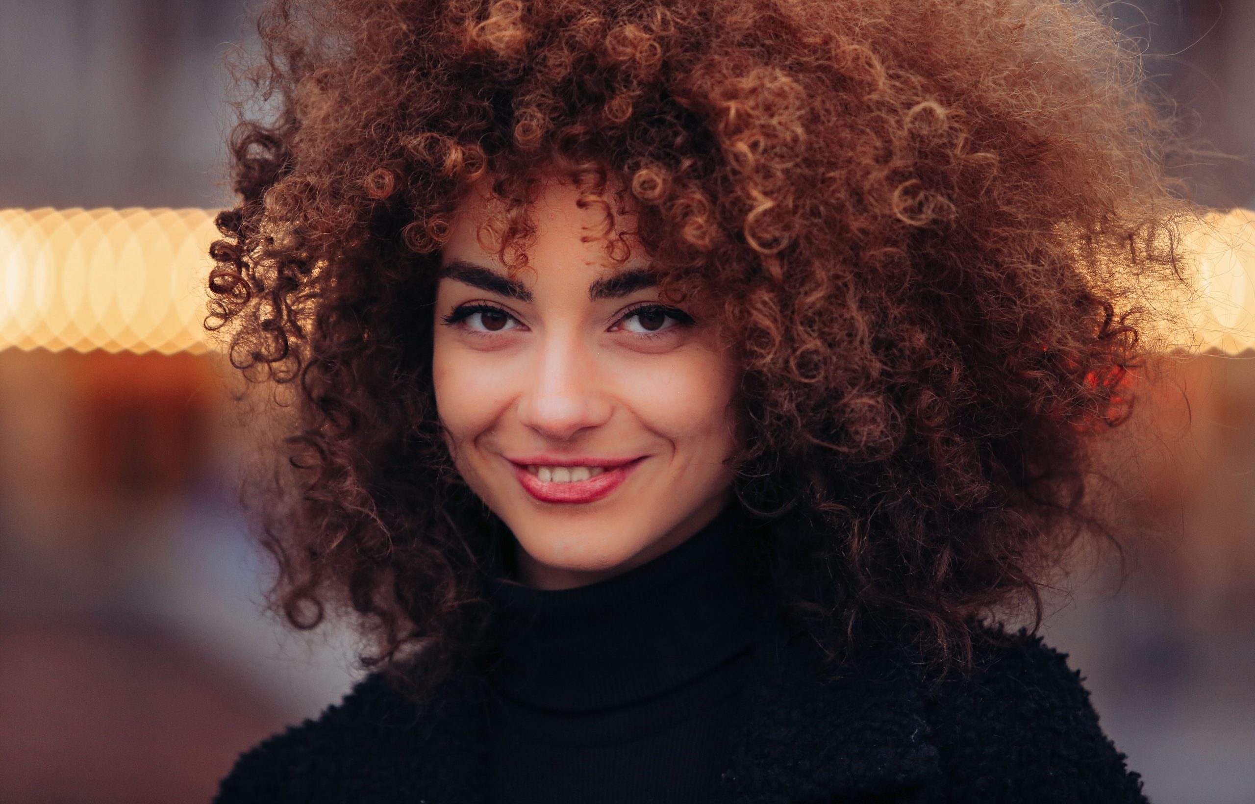 Femme souriante cheveux boucles naturels vetement noir