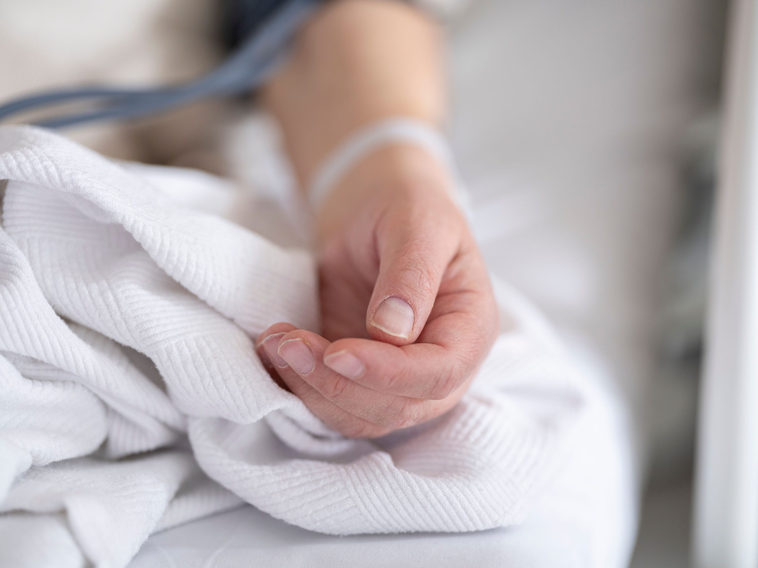 Main patiente avec perfusion sur lit d'hôpital