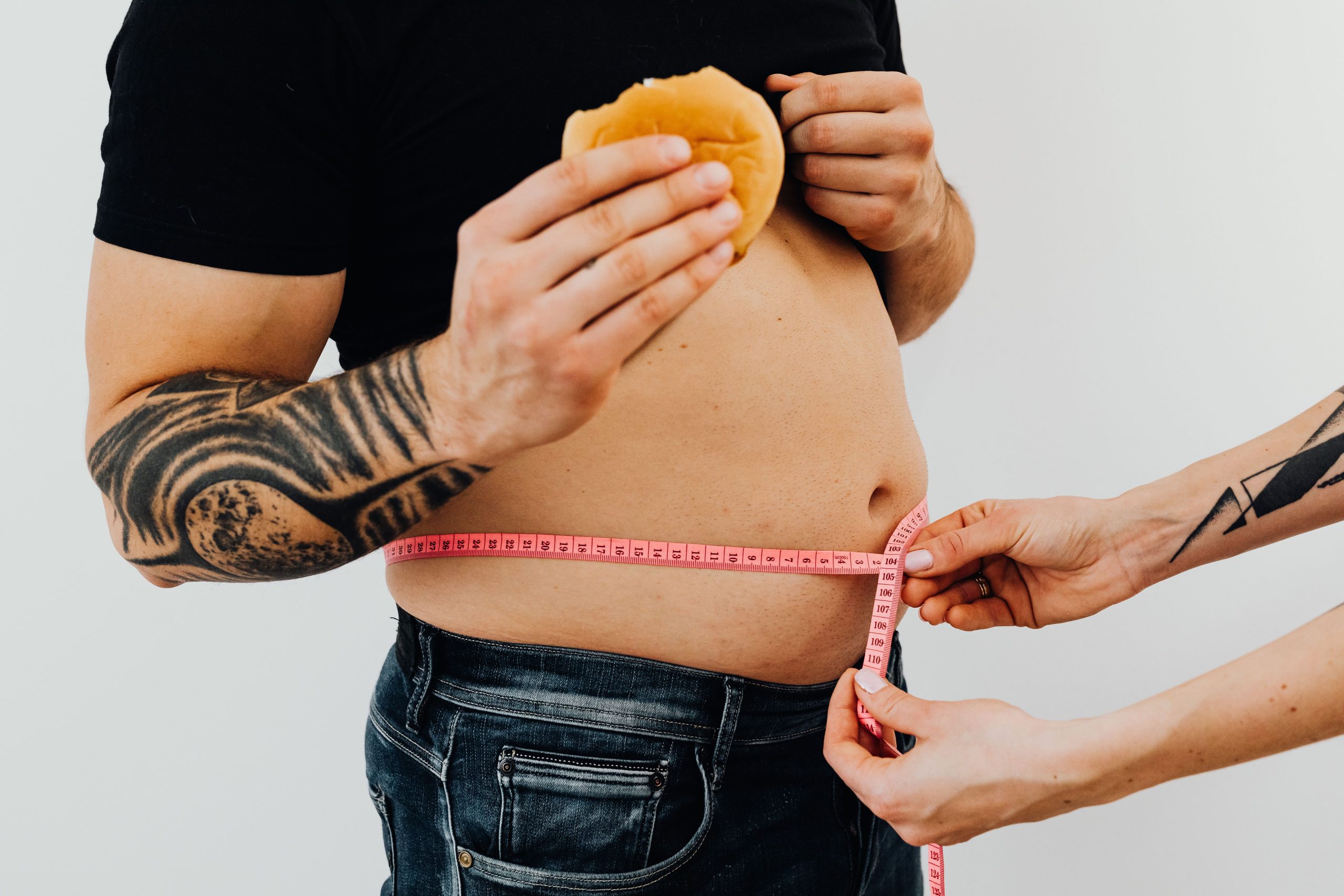 Homme tatoué mangeant burger pendant mesure taille